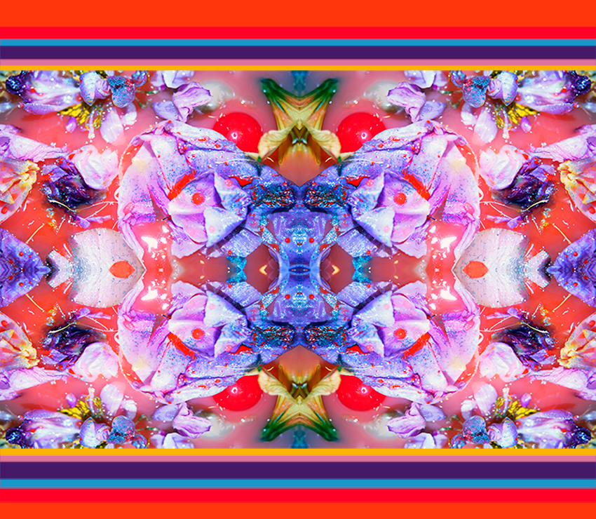 Jacquarddeken met kleurrijk bloemmotief in roze, paars, rood en oranje. Caleidoscopisch patroon en kleurrijke randen.